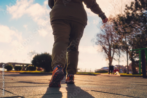 A overweight woman in sports clothes, standing ready to run. Legs close-up. Low angle view. The concept of fitness and weight loss