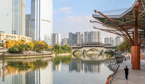 Elderly Man practicing tai chi by the iconic city view of the Anshun Bridge over Jinjiang River in Chengdu  a mega city in Sichuan  China   with modern skyscrapers and buildings in the background