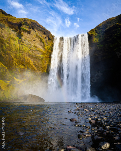 Fototapeta Naklejka Na Ścianę i Meble -  A person admirnig the beauty of Skogafoss waterfall located in Iceland. Girl tourist enjoying freedom on vacation at waterfall