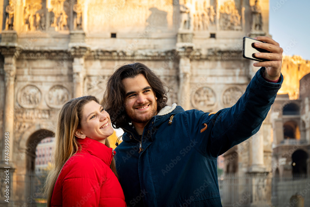Say cheese! Young charming couple making a selfie in the historical center of Rome, near the Arch of Titus.