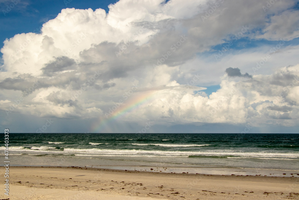 A Rainbow over the ocean, seen from the beach. 