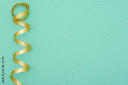 Gold ribbon on a mint green background. Abstract festive postcard image with space for text.