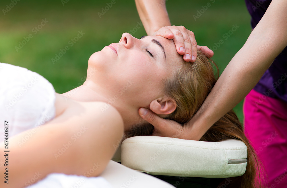 Woman is relaxing on massage table, couch masseur is doing massage massaging female neck, head and face in spa salon outdoors. Natural background. Spa treatment, health, body care Woman is relaxing on massage table, couch masseur is doing massage massaging female neck, head and face in spa salon outdoors. Natural background. Spa treatment, health, body care