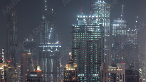 High multi-storey buildings under construction and cranes at night timelapse