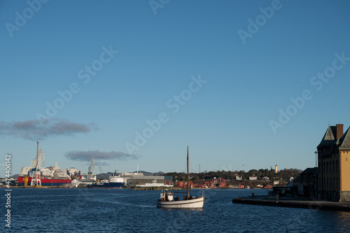 A small pleasure boat in the water. Stavanger port in the background.