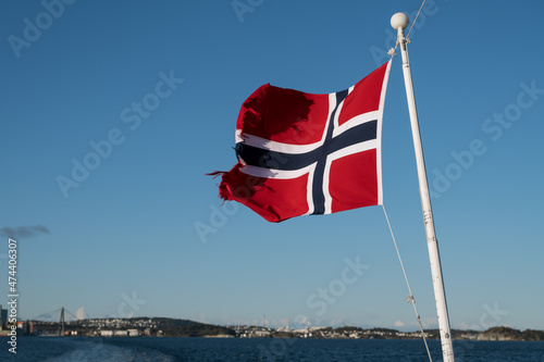 Waving flag of Norway on background of fjord. Cruise along the Lusefjord on a sunny day. Luxury tourism.