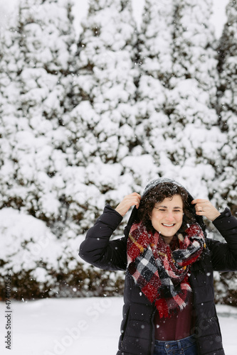 Woman in hood and red scarf smiling and laughing outside on snowy day