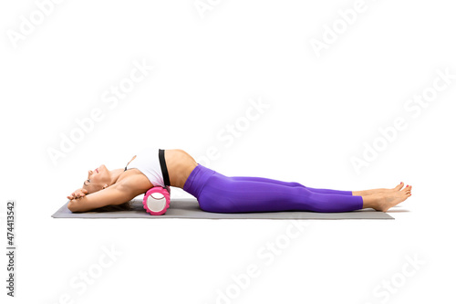 Mid back extension. Attractive fit woman lying on back and using pilates roller to stretch and relax her thoracic, isolated on white.