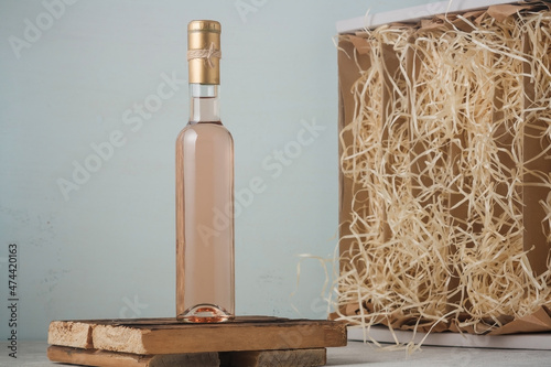 Bottle of pink wine with mock up blank label, no brand template, box with decoratives havings filler on wooden background photo