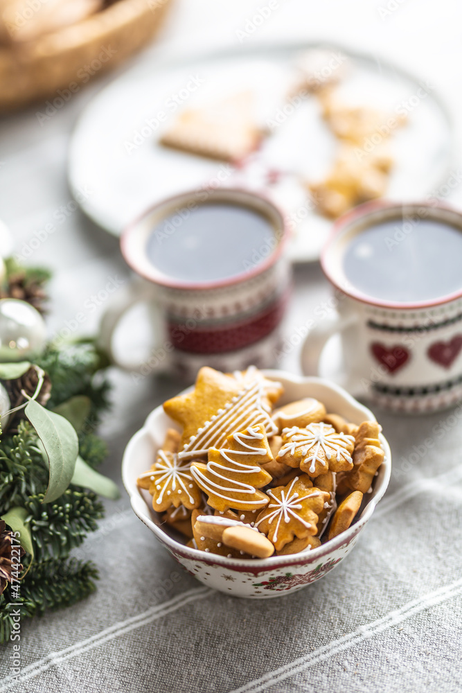 A bowl full of Christmas gingerbread on the table led an Advent wreath and two cups with coffee, punch or tea