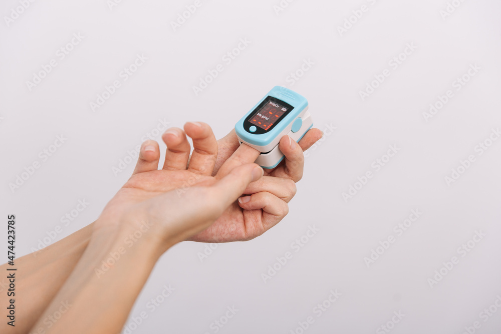 Pulse oximeter with hand of doctor isolated on white. Measuring oxygen saturation, pulse rate and oxygen levels. The concept of portable digital device to measure person's oxygen saturation Pulse oximeter with hand of doctor isolated on white. Measuring oxygen saturation, pulse rate and oxygen levels. The concept of portable digital device to measure person's oxygen saturation