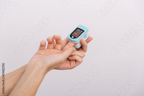 Pulse oximeter with hand of doctor isolated on white. Measuring oxygen saturation, pulse rate and oxygen levels. The concept of portable digital device to measure person's oxygen saturation