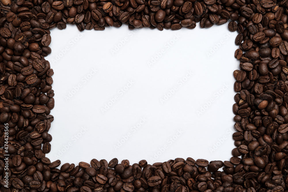 Roasted coffee beans surround a white frame. Copy space. Top view. 