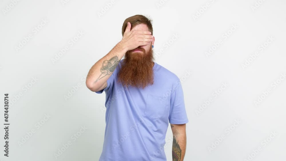 Redhead man with long beard covering eyes by hands. Surprised to see what is ahead over isolated background Redhead man with long beard covering eyes by hands. Surprised to see what is ahead over isolated background