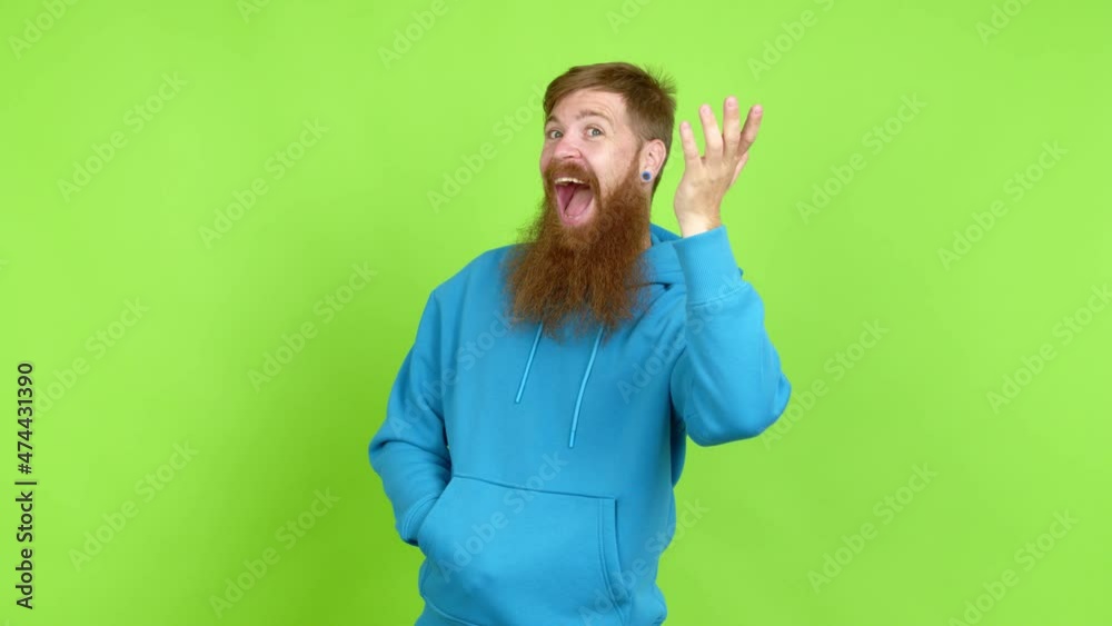 Redhead man with long beard saluting with hand with happy expression over isolated background Redhead man with long beard saluting with hand with happy expression over isolated background