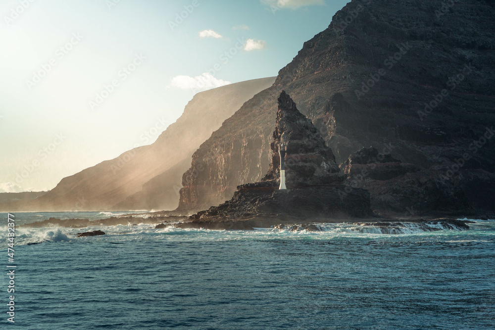 Fotografía horizontal de un Faro blanco en unos acantilados en la línea de costa de las Islas Canarias, España.