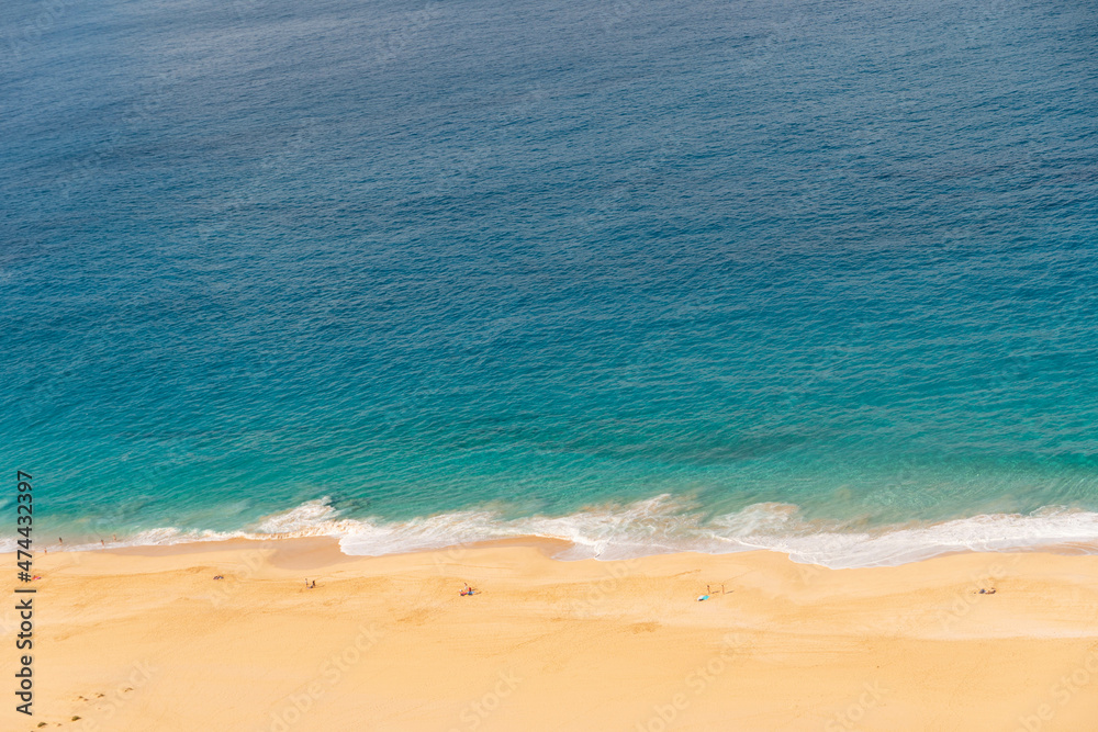 Vista aérea de playa con pocas personas, algunas olas y un mar azul 