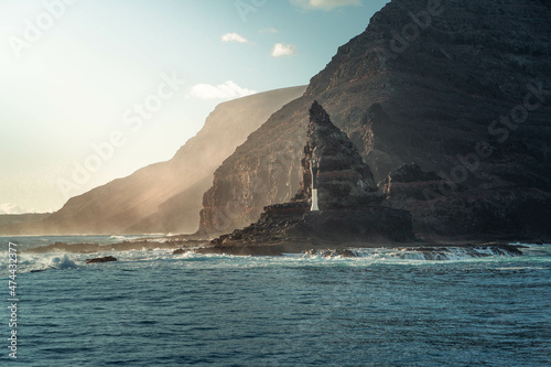 Fotografía horizontal de un Faro blanco en unos acantilados en la línea de costa de las Islas Canarias, España. photo