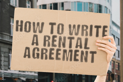 The phrase " How to Write a Rental Agreement " on a banner in men's hand with blurred background. Estate agent. Housing tenants. Living space. Place. Habitation. Tenement. Tenement. Room