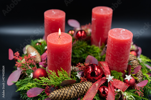Close up of beautiful advent wreath with one burning candle on black background