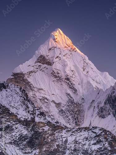Fototapeta Naklejka Na Ścianę i Meble -  Triangle snow peak in last sun light under dark blue sky in Nepal