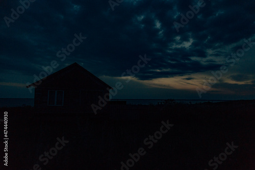 Old Wooden House by the Sea. Wonderful Sunset Landscape with a Dark Blue Sky