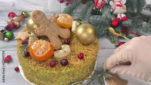 Cutting Christmas Honey Cake with Gingerbread man cookie and tangerines. Christmas decoration on background.
