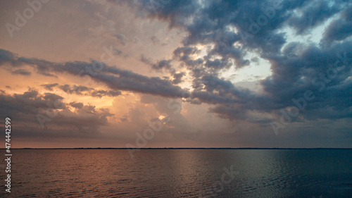 Beautiful Landscape of the Sunset on the Beach. Calm Weather with Dark Clouds in the Golden Sky Reflected in the Water