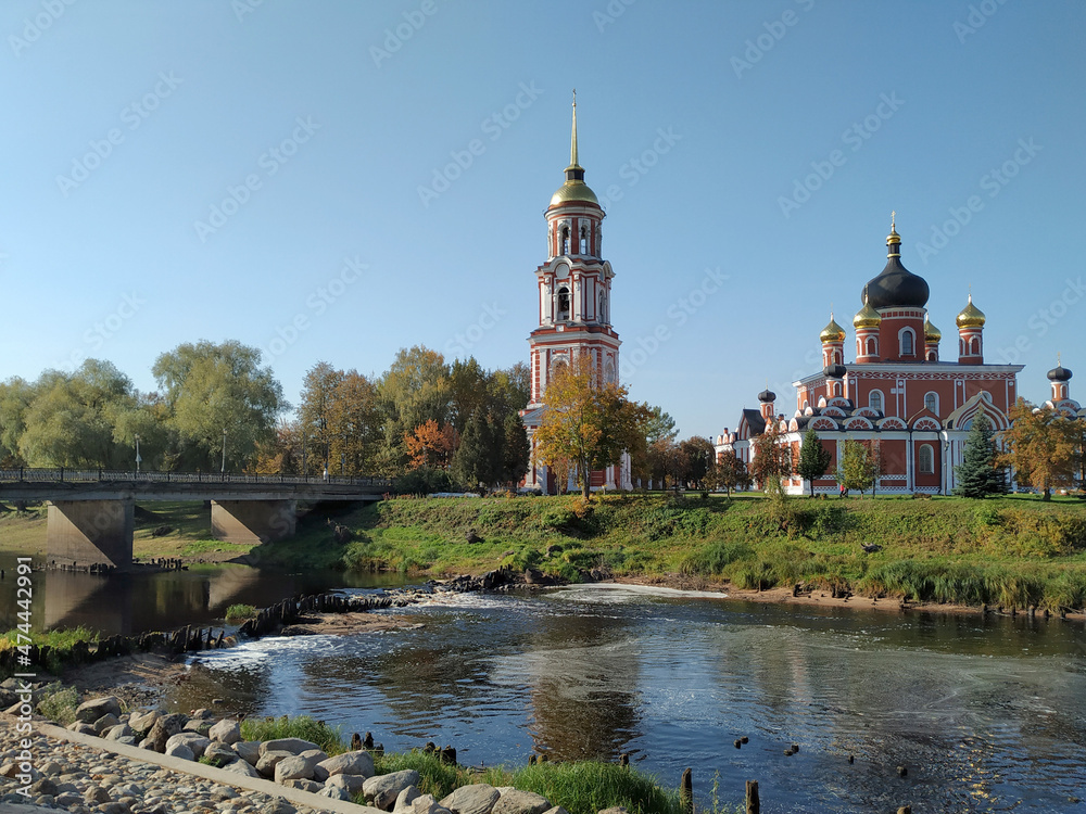 The ancient Orthodox Cathedral of the Resurrection of Christ with a brick-colored bell tower stands on the riverbank in the ancient city of Staraya Russa. Ancient Russian architecture. Russia.	