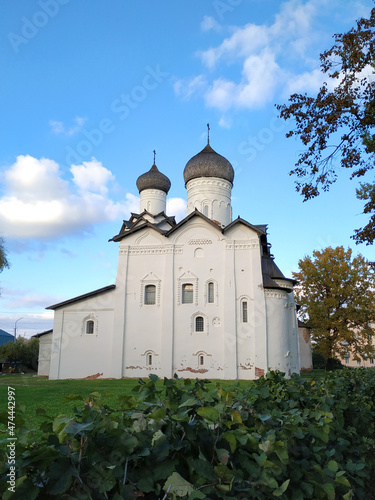 View of the ancient Spaso-Preobrazhensky Monastery with wooden domes, white facade, windows with platbands in the ancient city of Staraya Russa against a clear blue sky. Ancient Russian architecture o