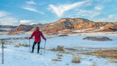 mature male hiker with trekking poles in Red Mountain Open Space, recreational area maintained by city of Fort Collins, Colorado - fall scenery at dusk with some snow