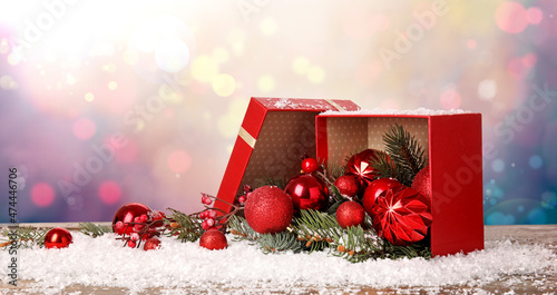Open gift box with Christmas decorations and snow on color background