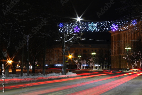 Traffic at city road at night, colorful lights and new Year decoration on city street 