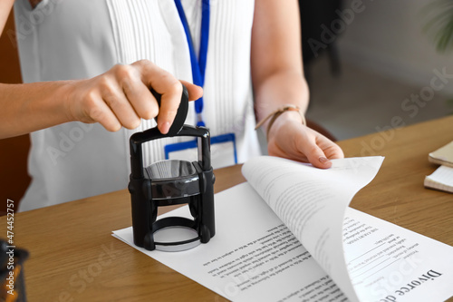 Female notary public attaching seal to document in office, closeup