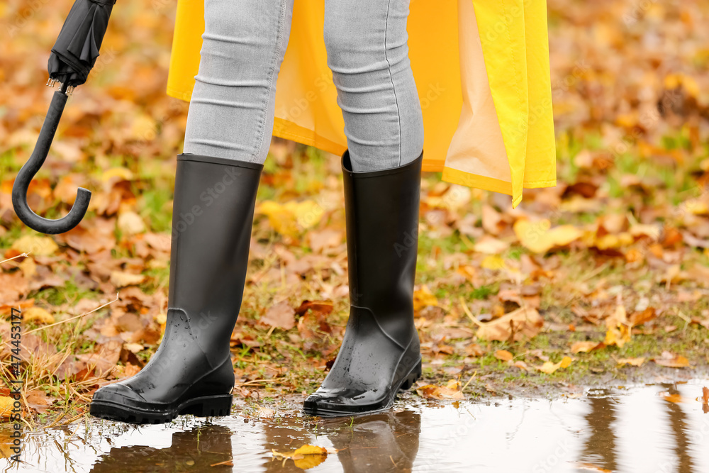 Woman wearing gumboots in park on autumn day