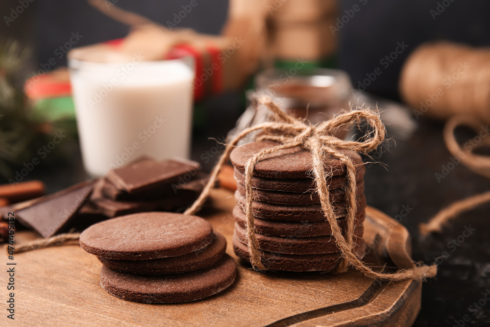 Wooden board with tasty chocolate cookies and on black background