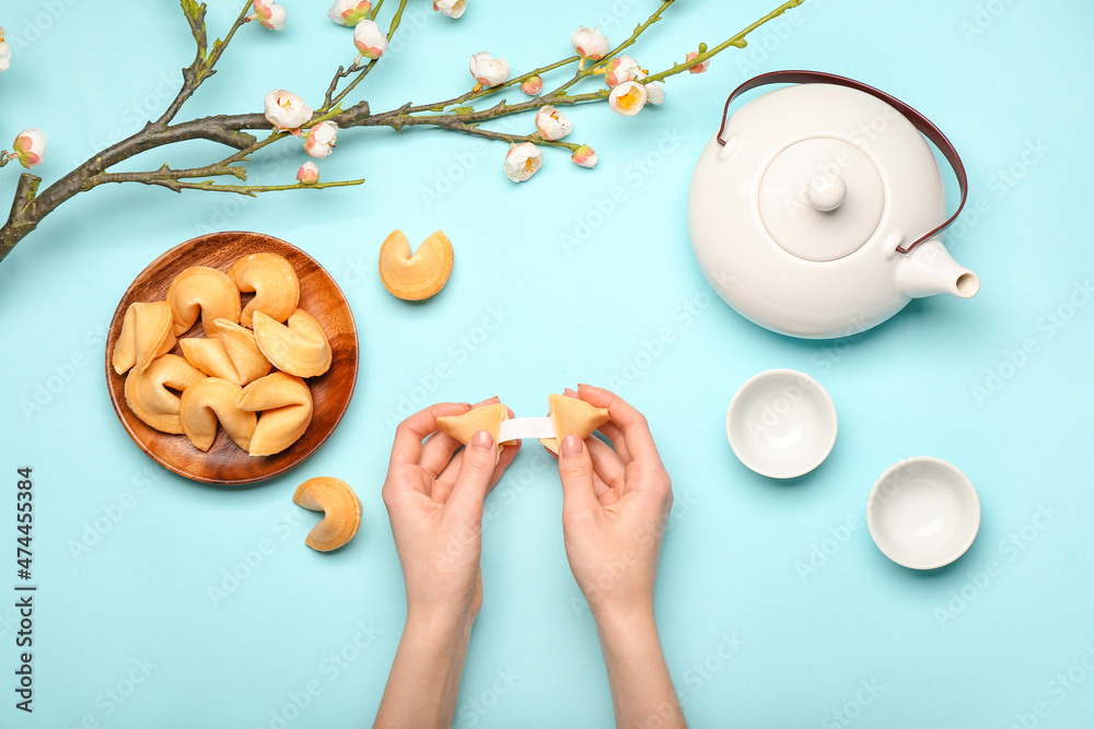 Female hands with Chinese fortune cookies and tea on color background