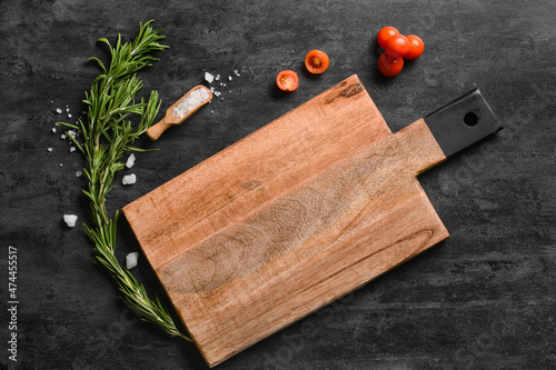 Fototapeta Wooden cutting board with tomatoes, sea salt and rosemary on dark background
