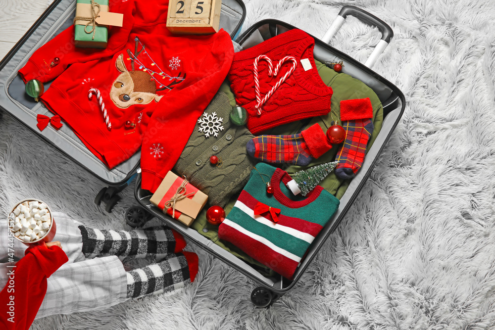 Naklejka premium Woman drinking hot chocolate and packing suitcase at home. Christmas holidays concept