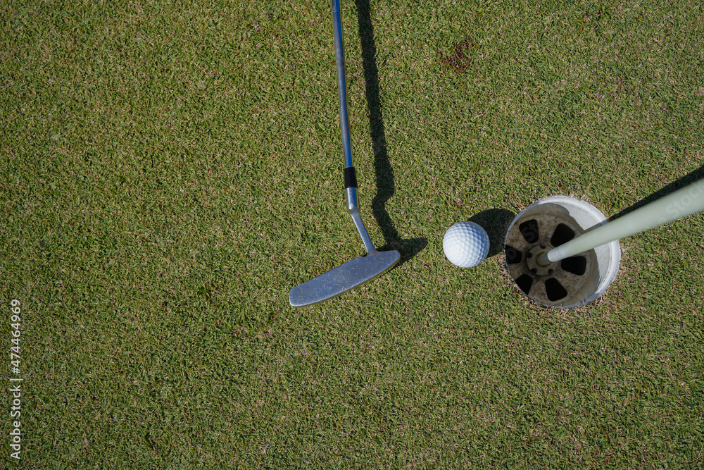 Obraz premium Golf ball and golf club on green in the evening golf course with sunshine in thailand.