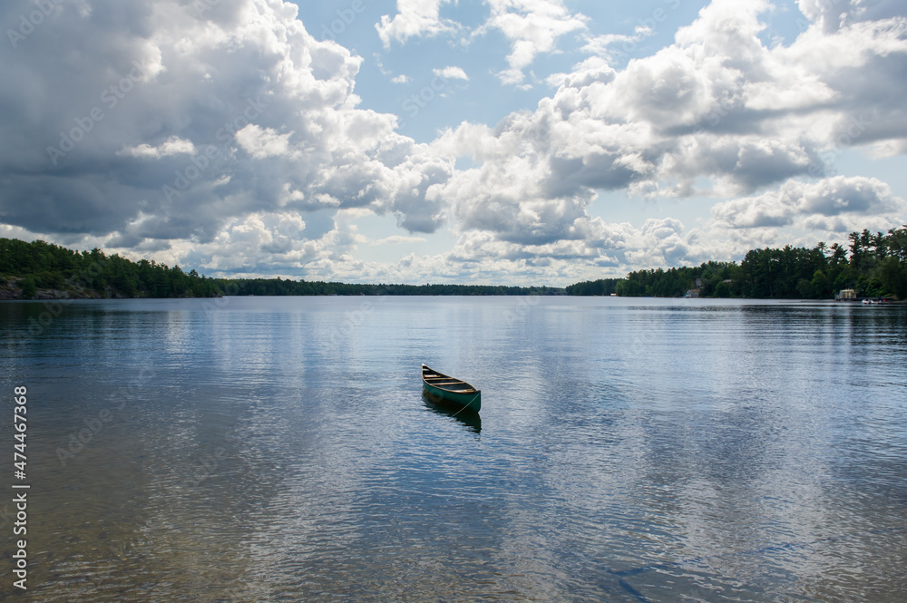 Green canoe tied to the shoreline on a lake in Muskoka - Ontario, Canada