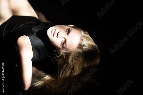 Elegant young woman posing over black background. Light and shadow. Portrait of a beauty woman face. Blonde sexy girl close up face. © Volodymyr