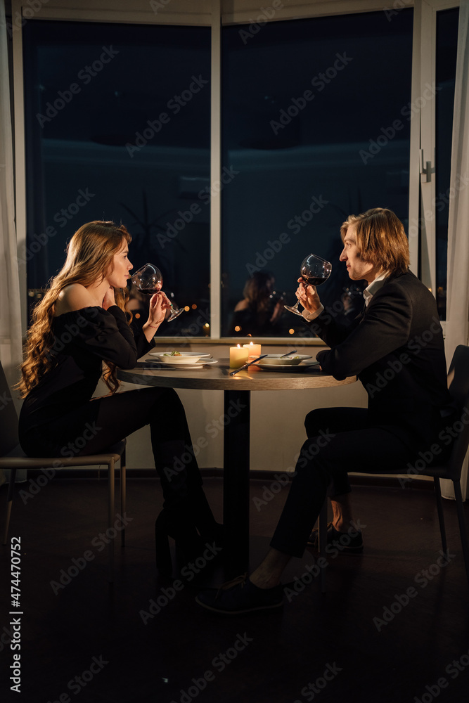 Romantic dinner for two couple drinking red wine, date at home at night at the table, Valentine's day celebration, man and woman relationship