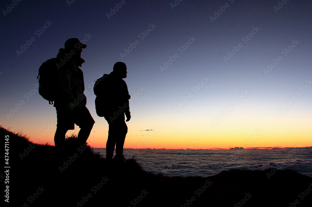 Silhouette of 2 Hikers in the Mountain with a Sea of Clouds Silhouette of 2 Hikers in the Mountain with a Sea of Clouds