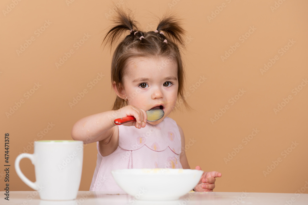 Cute baby food, babies eating. Happy infant baby girl with spoon eats itself.