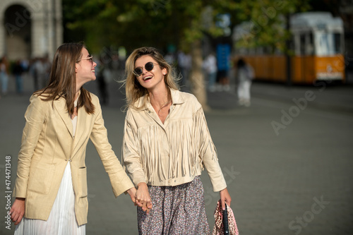 Laughing Girls with expressing positive emotions walking on the city street. Travelling in europe, budapest city. Funny vacation, romantic travel.