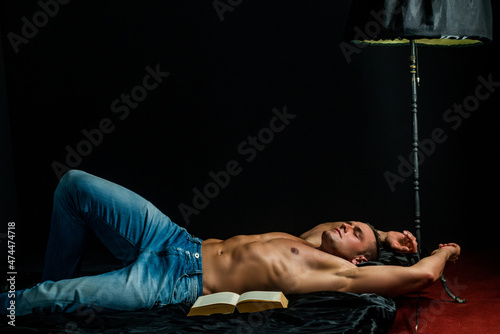 Muscular sleeping sexy guy, lying in bed on black background, naked torso.
