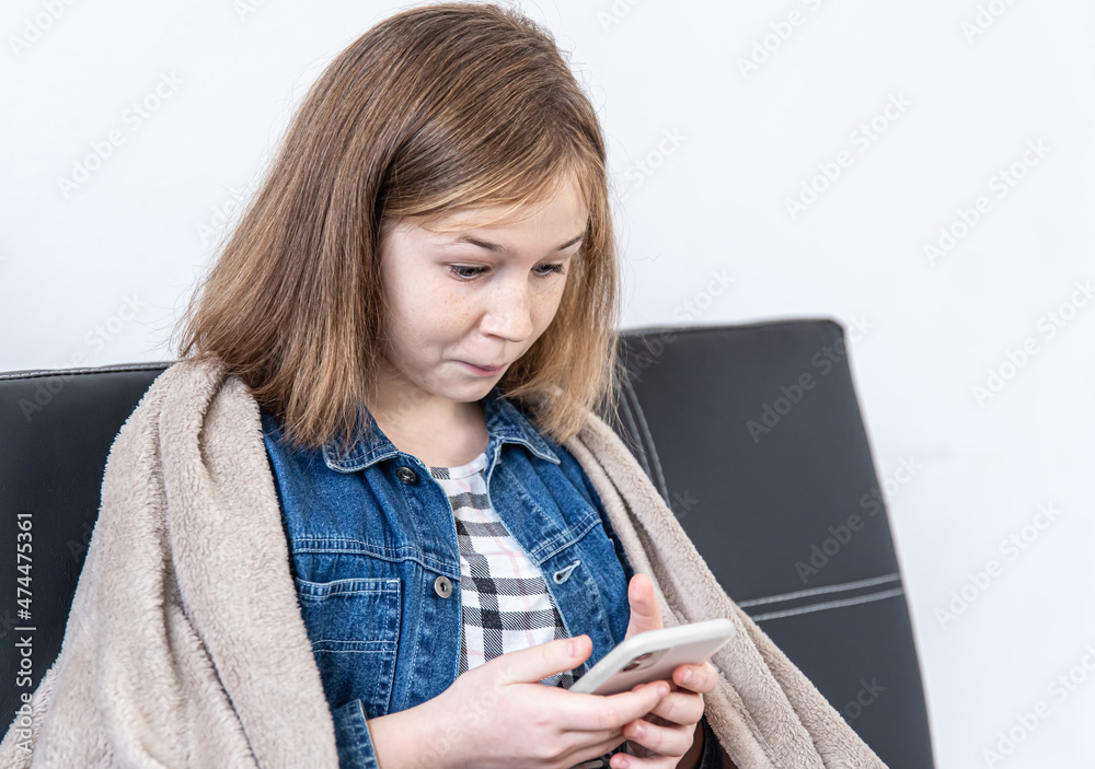 A teenage girl looks at the smartphone screen in surprise. A teenage girl looks at the smartphone screen in surprise.