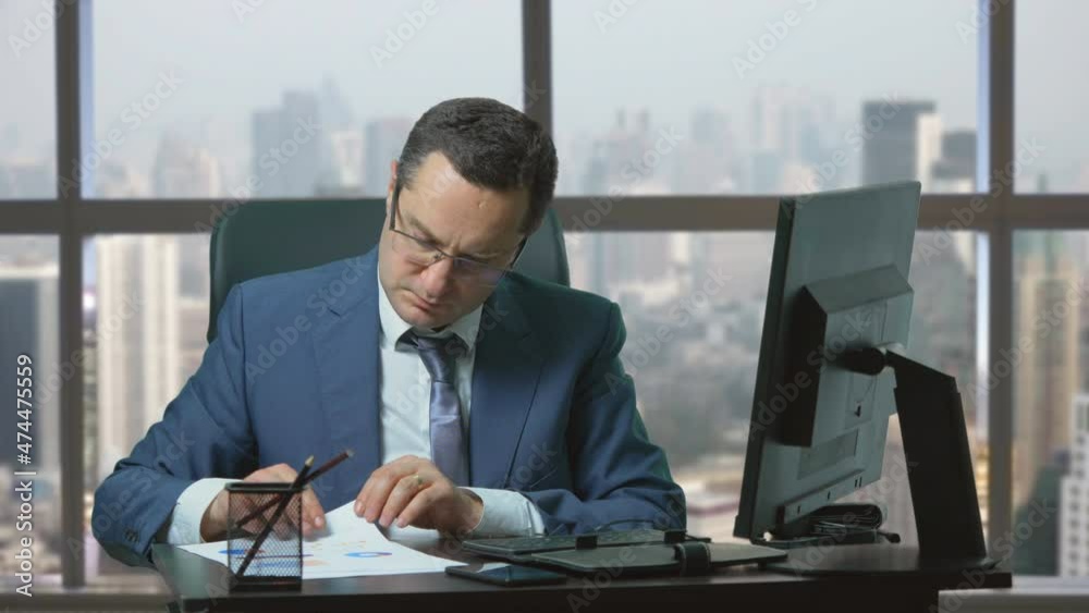 Manager with suit look at papers with graphic statistics at office, panoramic Manager with suit look at papers with graphic statistics at office, panoramic