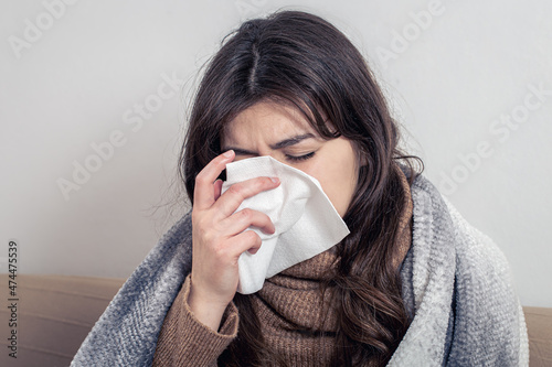 A sick young woman at home on the sofa with a cold.